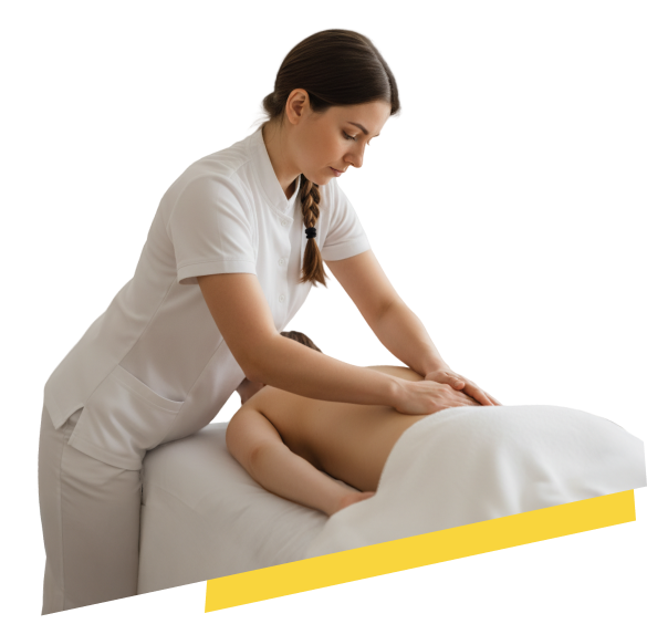 Terapeuta de masajes en uniforme blanco con cabello recogido en trenza, aplicando presión con el antebrazo y la palma en la espalda de un paciente boca abajo en una camilla. El entorno es un espacio de bienestar luminoso con paredes de ladrillo blanco pintado y plantas en macetas.
